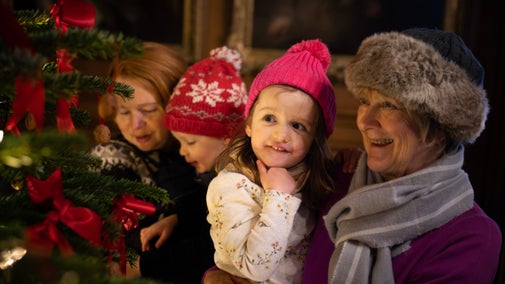 Children and adults close up by Christmas tree at Dyrham Park, South Gloucestershire